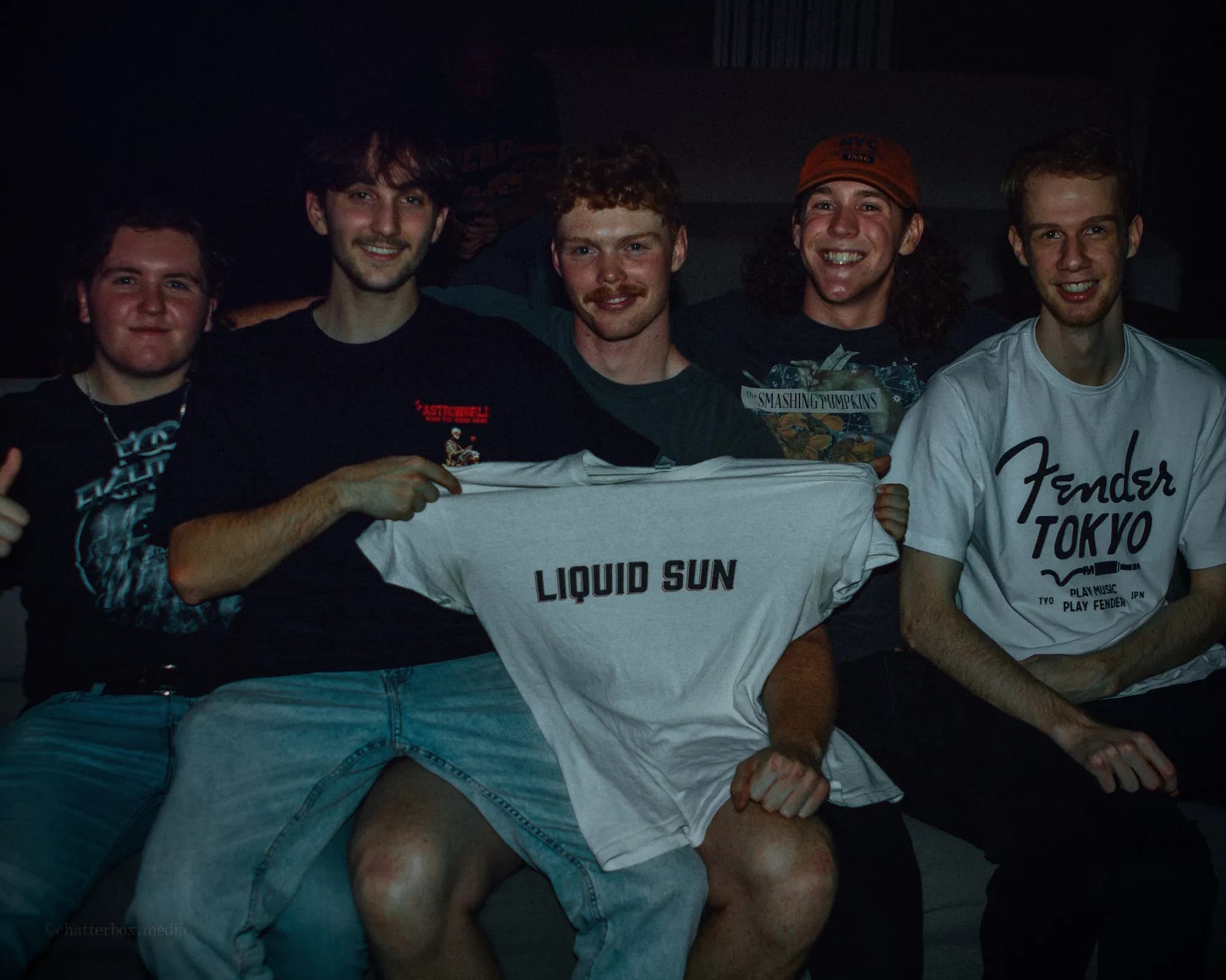 The five Liquid Sun band members together, holding a Liquid Sun shirt.